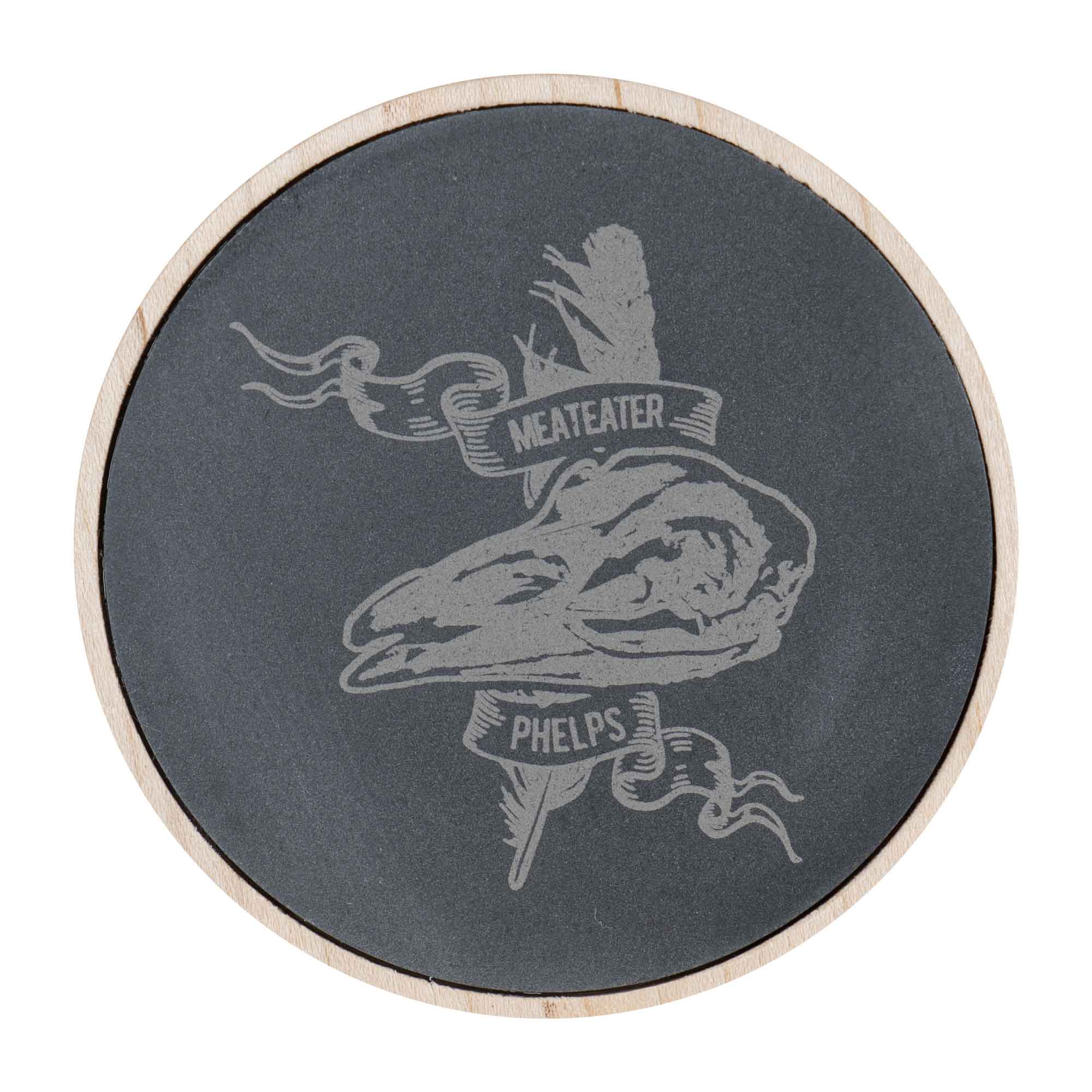 Round dark grey slate coaster with wood trim, engraved animal skull, "MEATEATER" and "PHELPS" banners.