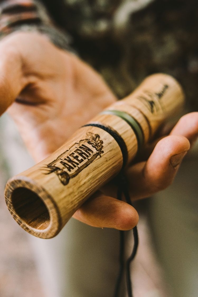 Man's hand holding a n Aker-n-grunt deer call with "AKERN" text on it.